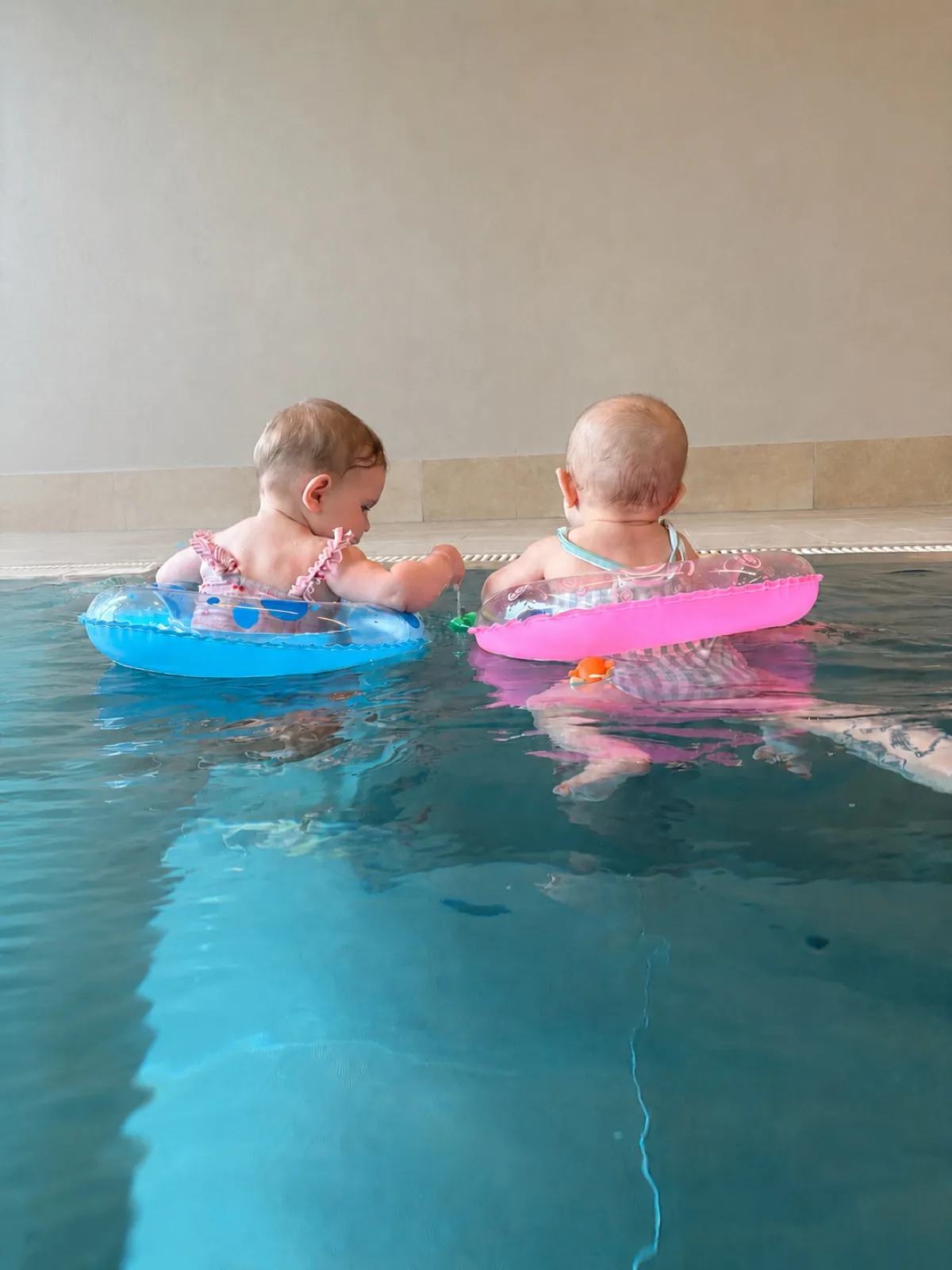 Zwei Babys sitzen mit Schwimmringen im Wasser beim Babyschwimmen