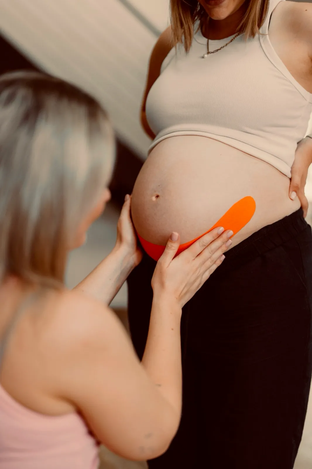 Verena klebt einer Schwangeren ein orangefarbenes Tape an den Bauch
