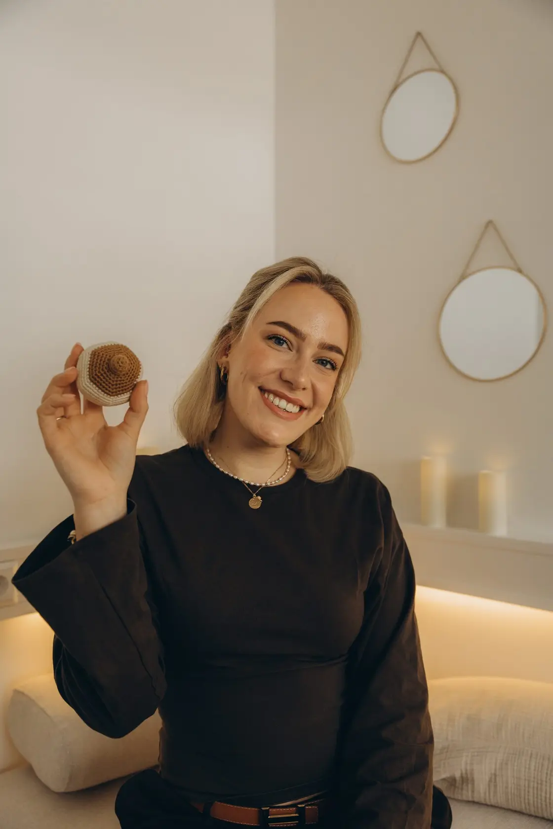Verena Radke lächelt in die Kamera, in der Hand ein gehäkeltes Brust-Modell für die Stillberatung