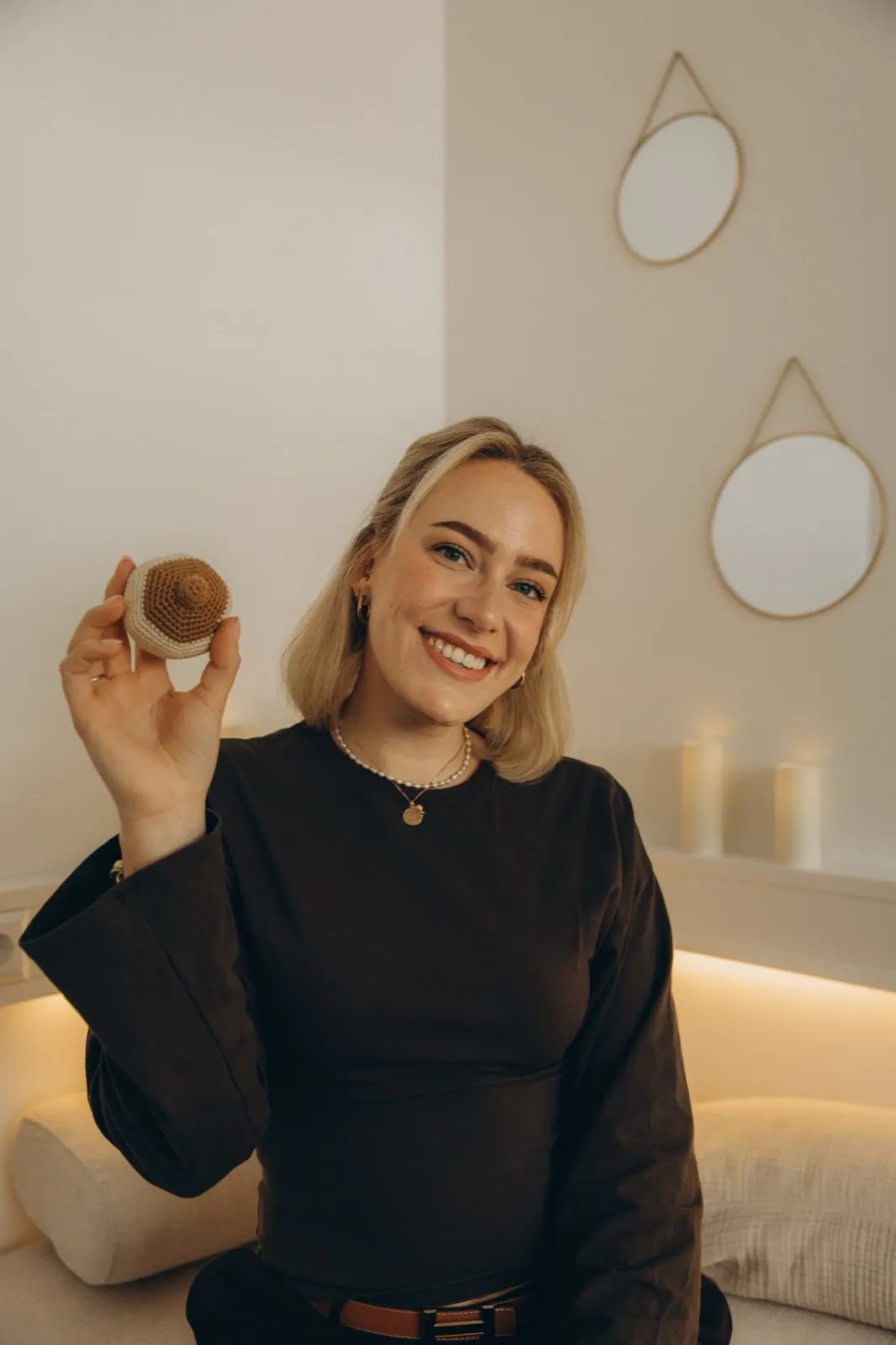 Verena Radke lächelt in die Kamera, in der Hand ein gehäkeltes Brust-Modell für die Stillberatung